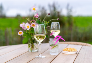 Tisch im Freien mit Weißweingläsern, Blumen, Snacks und Getränken bei 'By the Baker' in den Niederlanden.