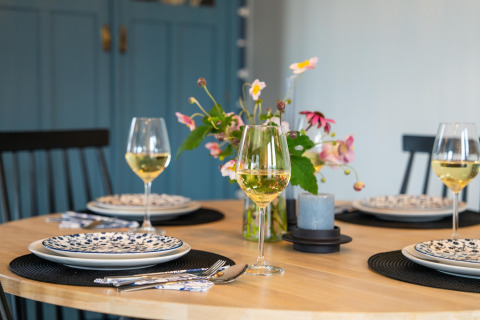 Elegant gedeckter Tisch mit Weingläsern, Blumen und blauen Schränken im 'By the Baker' Lodge in den Niederlanden.