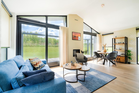 Salon lumineux et moderne avec baies vitrées, vue sur la verdure près des Kaag Lakes et des canaux de Leiden aux Pays-Bas.