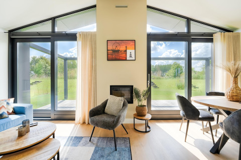 Salon moderne avec grandes fenêtres vitrées, décoration élégante et vue sur le jardin verdoyant