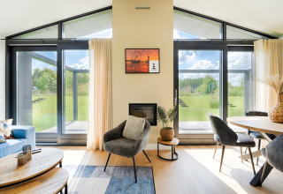 Salon moderne avec grandes fenêtres vitrées, décoration élégante et vue sur le jardin verdoyant