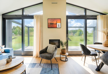 Salon moderne avec grandes fenêtres vitrées, décoration élégante et vue sur le jardin verdoyant