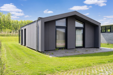 Maison de vacances moderne près des lacs Kaag et des canaux de Leiden aux Pays-Bas, entourée d’herbe verte.