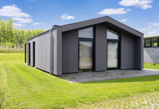 Maison de vacances moderne près des lacs Kaag et des canaux de Leiden aux Pays-Bas, entourée d’herbe verte.