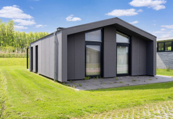 Maison de vacances moderne près des lacs Kaag et des canaux de Leiden aux Pays-Bas, entourée d’herbe verte.