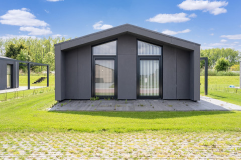 Maison de vacances moderne près des lacs Kaag et des canaux de Leiden aux Pays-Bas, pelouse et ciel bleu.