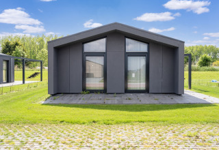 Maison de vacances moderne près des lacs Kaag et des canaux de Leiden aux Pays-Bas, pelouse et ciel bleu.