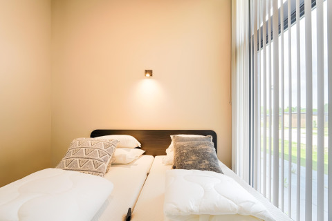Chambre moderne avec deux lits simples, coussins et grande fenêtre au Holiday home près des lacs Kaag, Pays-Bas.