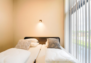 Chambre moderne avec deux lits simples, coussins et grande fenêtre au Holiday home près des lacs Kaag, Pays-Bas.