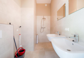 Licht en modern badkamer met twee wastafels, een douche en schoonmaakmateriaal vlakbij de Kaagplassen.