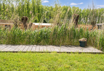 Terraza de madera con césped alto y maceta en lodge cerca de Kaag Lakes y Leiden Canals, Países Bajos.