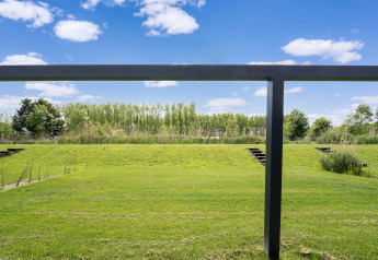 Blick auf eine grüne Rasenfläche mit Treppenstufen und Stahlrahmen im Holiday Home nahe Kaag-Seen, Niederlande.