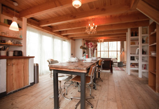 Gezellige houten eetruimte in de De Schone Leij cabin, Nederland, met rustieke meubels en grote ramen.