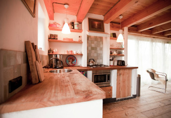 Rustic wooden kitchen with open shelves, modern appliances, and cozy lighting in a Dutch cabin.