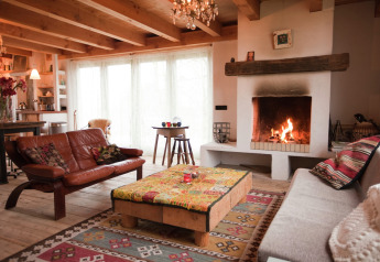 Cozy cabin living room with a fireplace, leather sofa, wooden coffee table and colorful rug at De Schone Leij, Netherlands.