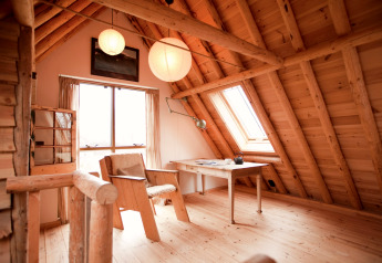 Gezellige houten zolderruimte met bureau in de hut De Schone Leij, Nederland, vol natuurlijk licht.