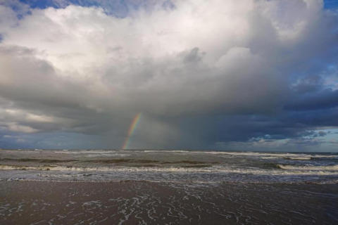 Uitzicht op zee met wolken en een regenboog, genomen vanaf de hut 'De Schone Leij' in Nederland.