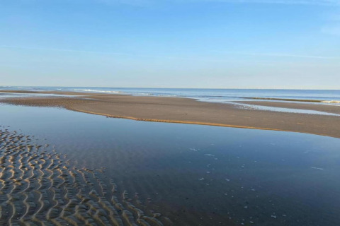 Foto van een rustige strand met zandbanken en ondiep water, genomen bij het huisje 'De Schone Leij' in Nederland.