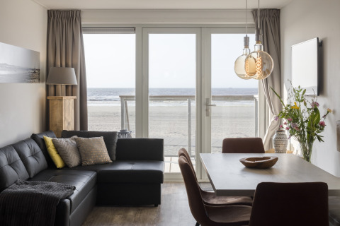 Modernes Wohnzimmer mit Meerblick durch große Fenster im Resort Hoek van Holland in den Niederlanden.