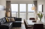 Sala de estar moderna con vista al mar a través de grandes ventanales en Resort Hoek van Holland, Países Bajos.