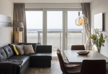 Sala de estar moderna con vista al mar a través de grandes ventanales en Resort Hoek van Holland, Países Bajos.