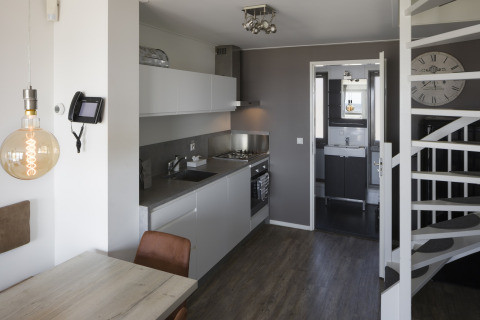 Moderne Küche und Essbereich in einem Strandhaus im Resort Hoek van Holland, Niederlande, mit Treppe und Bad.