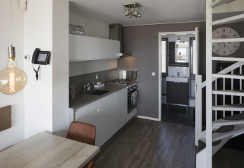 Cocina y comedor modernos en una casa de playa del Resort Hoek van Holland, Países Bajos, con escalera y baño.