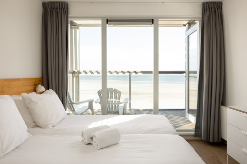 Helles Schlafzimmer mit zwei Betten, Meerblick und Balkon, Resort Hoek van Holland, Niederlande.