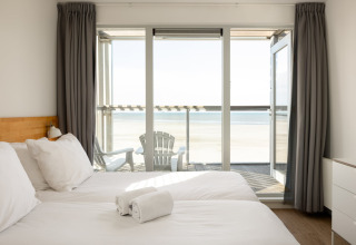 Helles Schlafzimmer mit zwei Betten, Meerblick und Balkon, Resort Hoek van Holland, Niederlande.