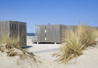 Casas de playa modernas en Resort Hoek van Holland, Países Bajos, con dunas y vista al mar detrás.