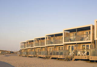 Moderne Strandhäuser im Resort Hoek van Holland, Niederlande, mit Terrassen am Sandstrand bei Sonnenuntergang.