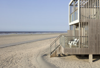 Modernes Strandhaus mit Holzfassade und Balkon am Sandstrand im Resort Hoek van Holland, Niederlande.