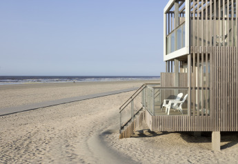 Casa de playa moderna con fachada de madera y balcón en Resort Hoek van Holland, playa de Holanda.