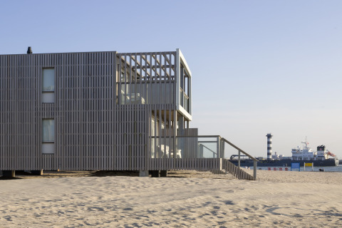 Modernes Strandhaus Resort Hoek van Holland in den Niederlanden mit Blick auf Sand und vorbeifahrendes Schiff.