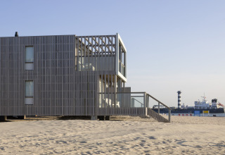 Modernes Strandhaus Resort Hoek van Holland in den Niederlanden mit Blick auf Sand und vorbeifahrendes Schiff.