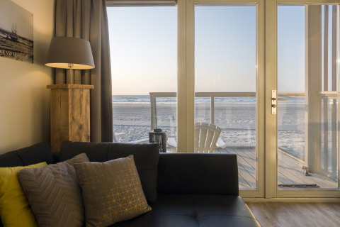 Wohnzimmer im Strandhaus Resort Hoek van Holland mit Blick auf den Strand durch Glastüren, Niederlande.