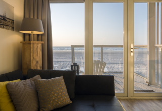 Wohnzimmer im Strandhaus Resort Hoek van Holland mit Blick auf den Strand durch Glastüren, Niederlande.