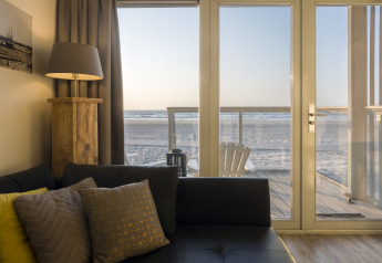 Sala de estar en una casa de playa en Resort Hoek van Holland con vista a la playa por puertas de cristal, Países Bajos.