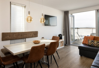 Sala y comedor modernos en una casa de playa del Resort Hoek van Holland en Países Bajos, con vistas al mar.