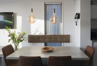 Moderner Essbereich im Strandhaus Resort Hoek van Holland mit Blumen, Lampen und braunen Stühlen.