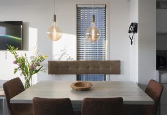 Comedor moderno en casa de playa Resort Hoek van Holland, con flores, lámparas y sillas marrones.