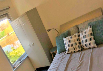 Camera da letto presso Villa «Avondrood» nei Paesi Bassi con letto, cuscini, armadio e vista sul giardino.
