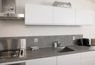 Moderne Küchenarbeitsplatte mit Spüle, Gasherd und weißen Schränken im Resort Hoek van Holland.