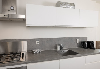 Encimera de cocina moderna con fregadero, estufa de gas y armarios blancos en Resort Hoek van Holland.