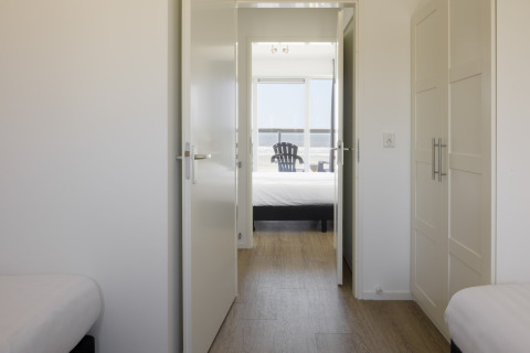 Blick aus einem hellen Zimmer im Resort Hoek van Holland mit offenen Türen und Meerblick im Hintergrund.