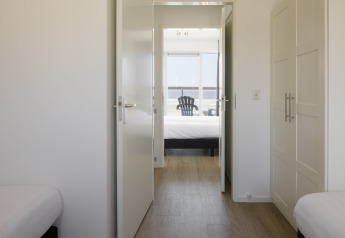 Vista desde una habitación luminosa en el Resort Hoek van Holland con puertas abiertas y vista al mar al fondo.