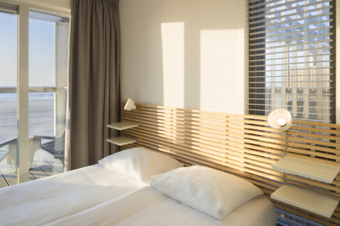 Schlafzimmer im Strandhaus Resort Hoek van Holland, Niederlande, mit Blick aufs Meer und modernen Möbeln.