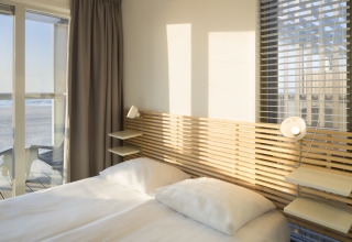 Schlafzimmer im Strandhaus Resort Hoek van Holland, Niederlande, mit Blick aufs Meer und modernen Möbeln.