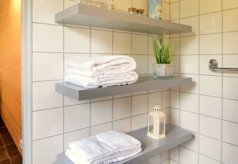 Mensole da bagno moderne con asciugamani bianchi, lanterna decorativa e pianta a Villa Avondrood, Paesi Bassi.