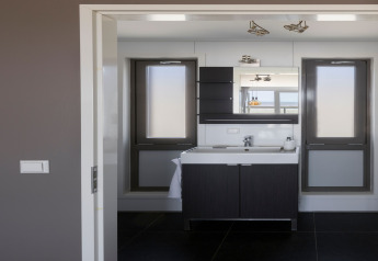 Baño moderno con lavabo, espejo y ventanas en la casa de playa Resort «Hoek van Holland», Países Bajos.